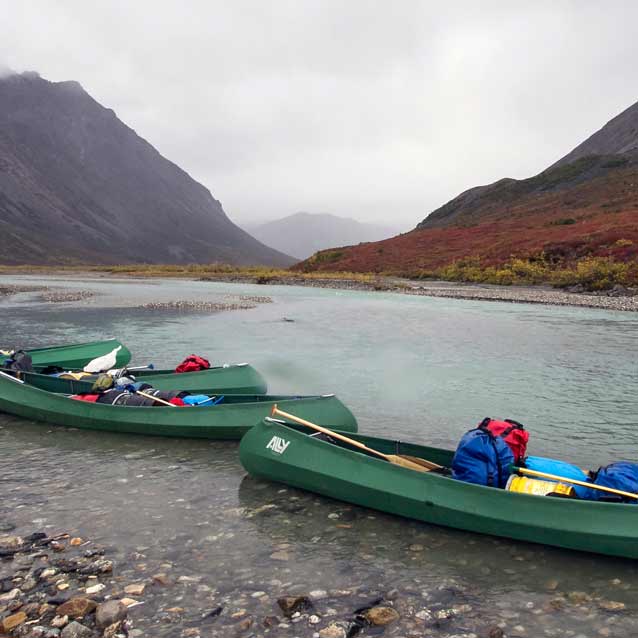 three large canoes in shallow water