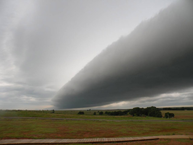 A large, oblong storm cloud over grasslands at Washita Battlefield National Historic Site.