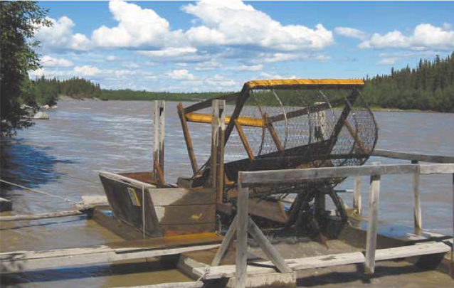 A fishwheel sits on the bank of the river