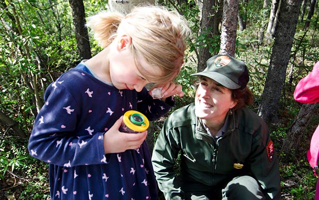 a ranger watches on as a students makes new discoveries using a magnifying box