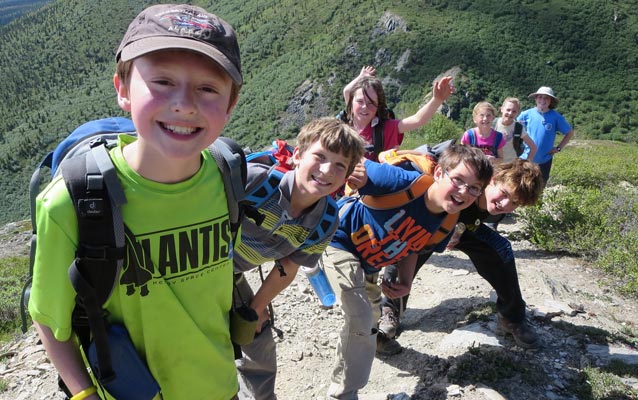 Campers lines up and wave as hiking up a mountain