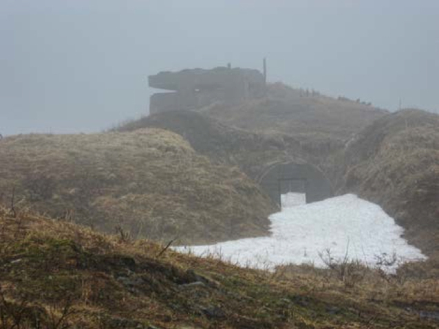 A concrete military structure on a hill, shrouded in fog.