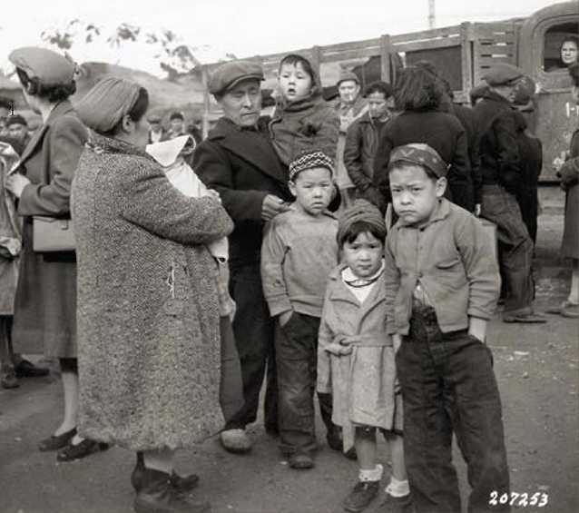 An Aleut family stands by truck. Four children look towards camera. An Aleut family stands by truck. Four children look towards camera.