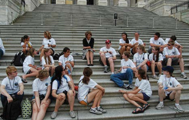 A group of young adults sit around Alaska Senator Lisa Murkowski on steps of U.S. Captiol.