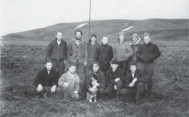 A group of men and a dog pose in two rows for photo. A group of men and a dog pose in two rows for photo.