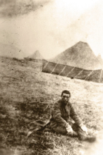 A Japanese man sits on the ground with his hands on his legs.