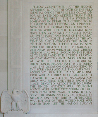 A carving of fasces and an eagle next to text carved into stone wall.