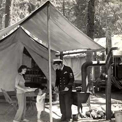 A sailor in uniform with woman and child in tent