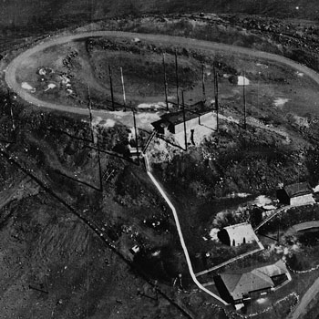 B&W photo of dirt road circling radio towers and small white building