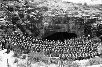 B&W large group of soldiers post in front of cave entrance B&W large group of soldiers post in front of cave entrance