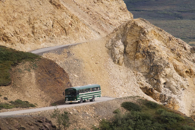 A bus winds around a dirt mountain road