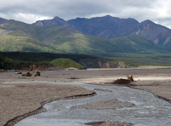 bulldozers scoop gravel in a river bed