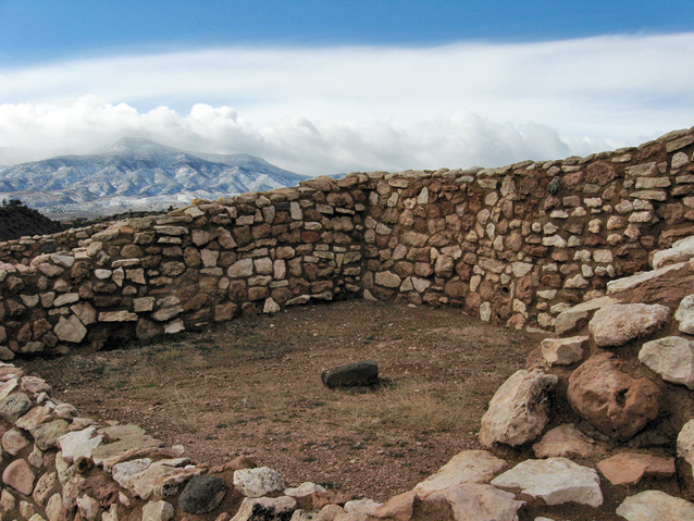 Walls of a room in Tuzigoot Pueblo, with a view of cloud-shrouded mountains in the distance Walls of a room in Tuzigoot Pueblo, with a view of cloud-shrouded mountains in the distance