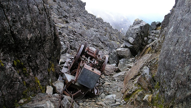 Large rusted metal item sits between large rocks. Large rusted metal item sits between large rocks.