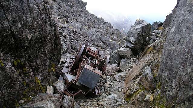 Large rusted metal item sits between large rocks.