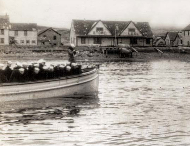 A boat filled with sailors approaches coast