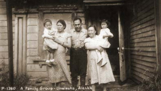 A family group, one man and two women holding children pose for camera.