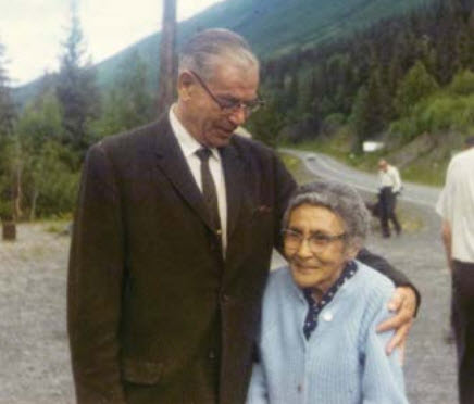 A man stands with his arm around an elderly woman. A man stands with his arm around an elderly woman.
