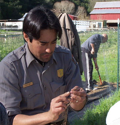 Keith Park, in NPS uniform, looks down at his hands as he demonstrates grafting technique.