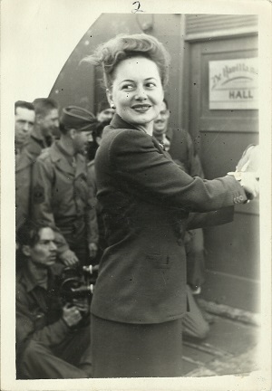 A woman stands, smiling