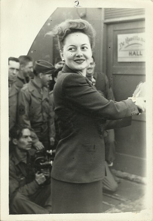 A woman stands, smiling A woman stands, smiling