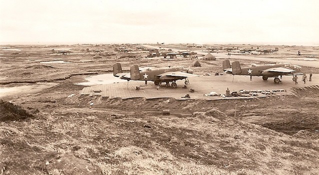 Planes sit on steel mats in a flat grassy area. Planes sit on steel mats in a flat grassy area.