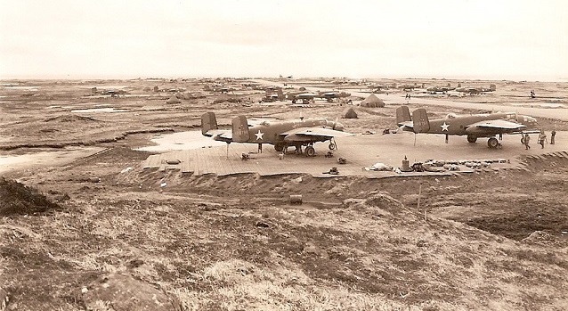 Planes sit on steel mats in a flat grassy area.