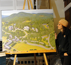 A woman stands next to a large canvas painting on an easel.