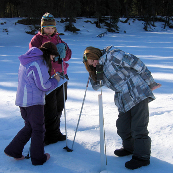 Students use a snow probe to measure snow depth and temperature.