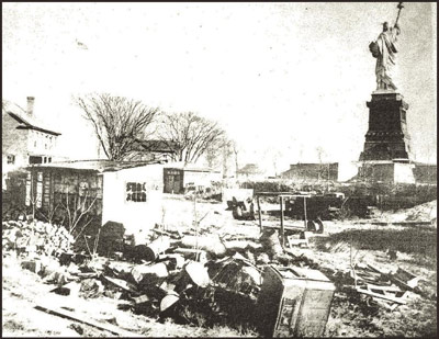 A view of the Statue of Liberty includes a pile of debris and partially disassembled buildings.
