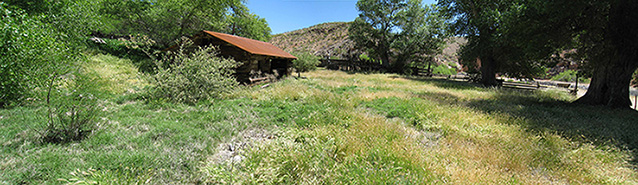 A panoramic of the ranch yard with the ranch house, tall grass, and scattered trees and shrubs. A panoramic of the ranch yard with the ranch house, tall grass, and scattered trees and shrubs.