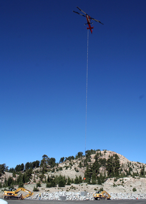 helicopter in the sky on a sunny day carrying a sling load of rocks