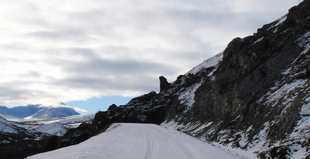 a rocky debris slide covers a snowy road