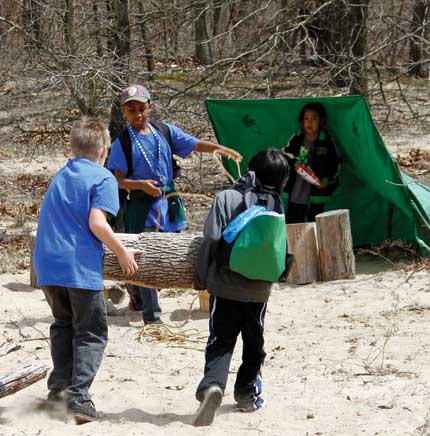 Children create a shelter using tarps and logs at Nature Play Zone 