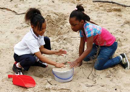 Two Gary, Indiana, students dig in the sand at the Nature Play Zone