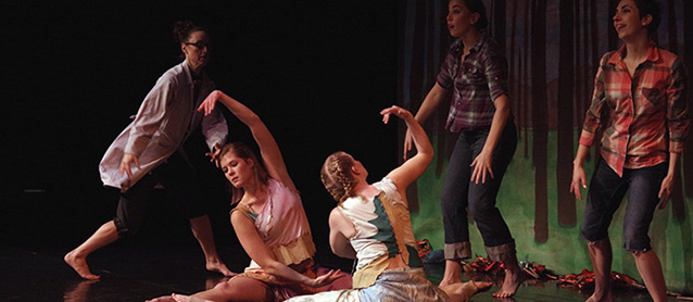 Two women perform choreographed moves on the floor while three other perform nearby.