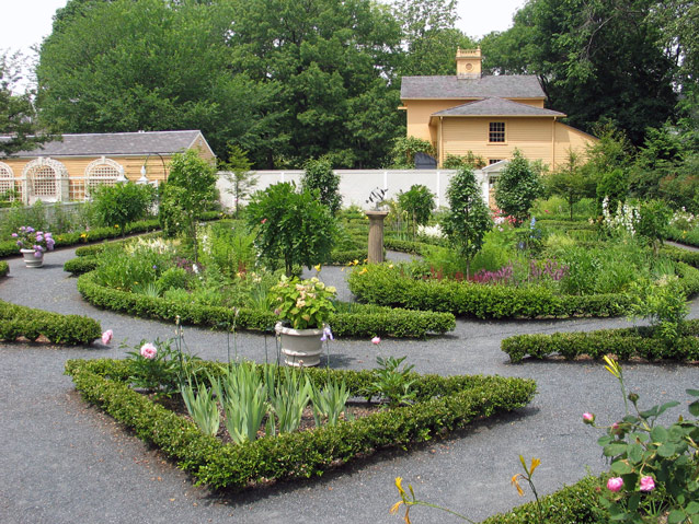 Geometric plantings in the formal garden are punctuated by planters, trees, and boxwood edging. 