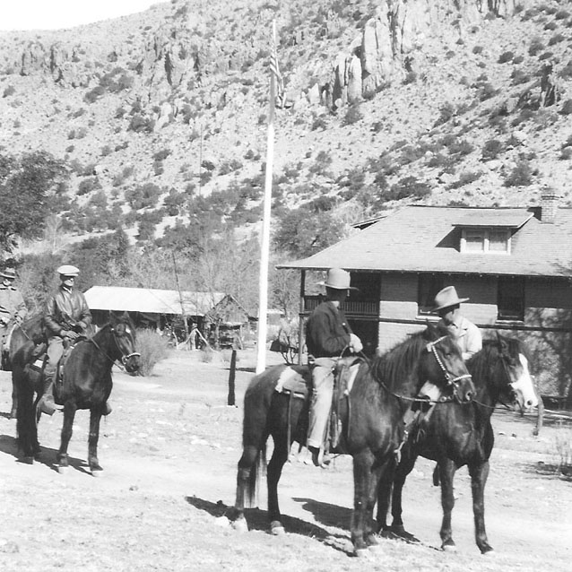 Three people on horses in front of Faraway Ranch buildings Three people on horses in front of Faraway Ranch buildings