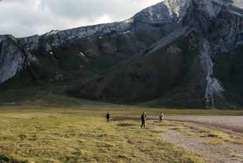 three people walking across tundra toward a mountain