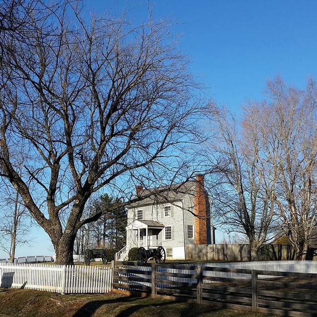 small two-story building surrounded by trees under a blue sky