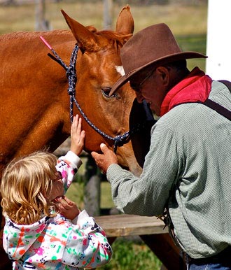 man and child next to a horse