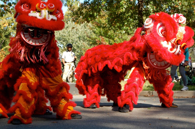  Choy Mei Leadership Institute performs traditional Chinese lion and dragon dance with synchronized drumming at Fort Dupont Park. Two lion dancers are in red costumes.