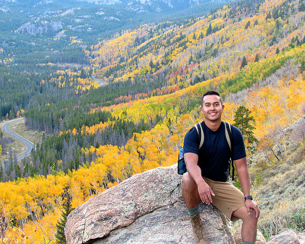 A man sits on a rock with autumn colors in the background