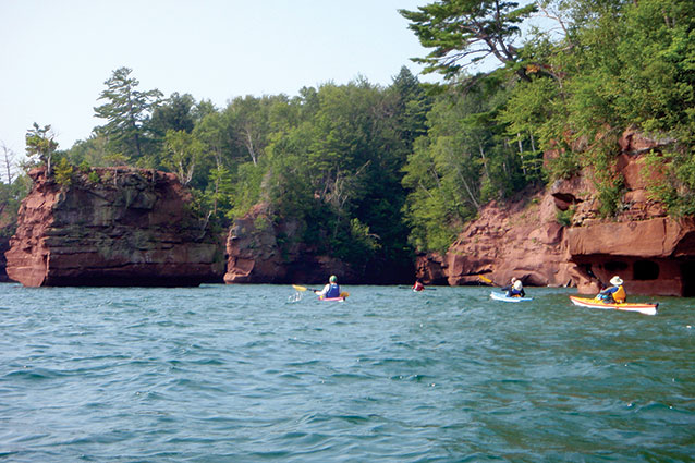 Kayakers paddle past sandstone rocks in Apostle Islands National Lakeshore