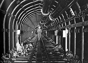 Black and white photo of a crew member standing in a long tunnel