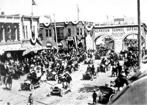 Black and white photo of a crowd of people next to a town of old houses