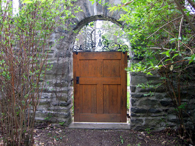 A wooden door in an arch of stone wall makes an ornate gate. 