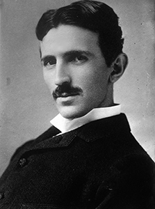 A black and white picture of Nicola Tesla who has dark hair and mustache 