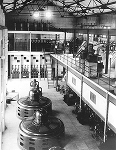 Black and white photo of the Minidoka Powerplant  interior with five vertical generators 