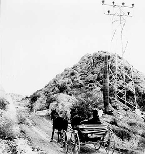 Black and white photo of a horse and carriage riding along the path in a dessert 